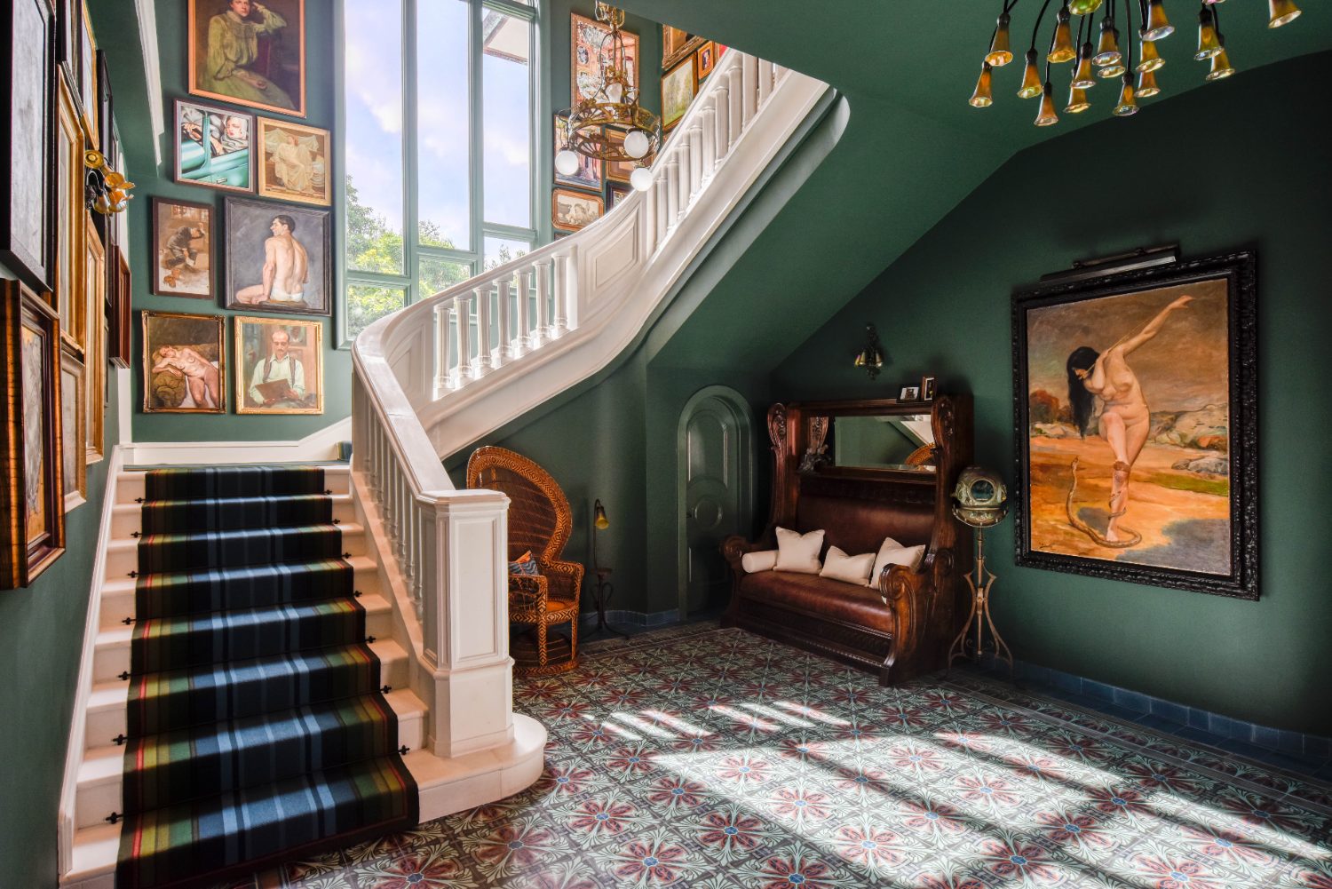 A green stair hall hung with framed artwork
