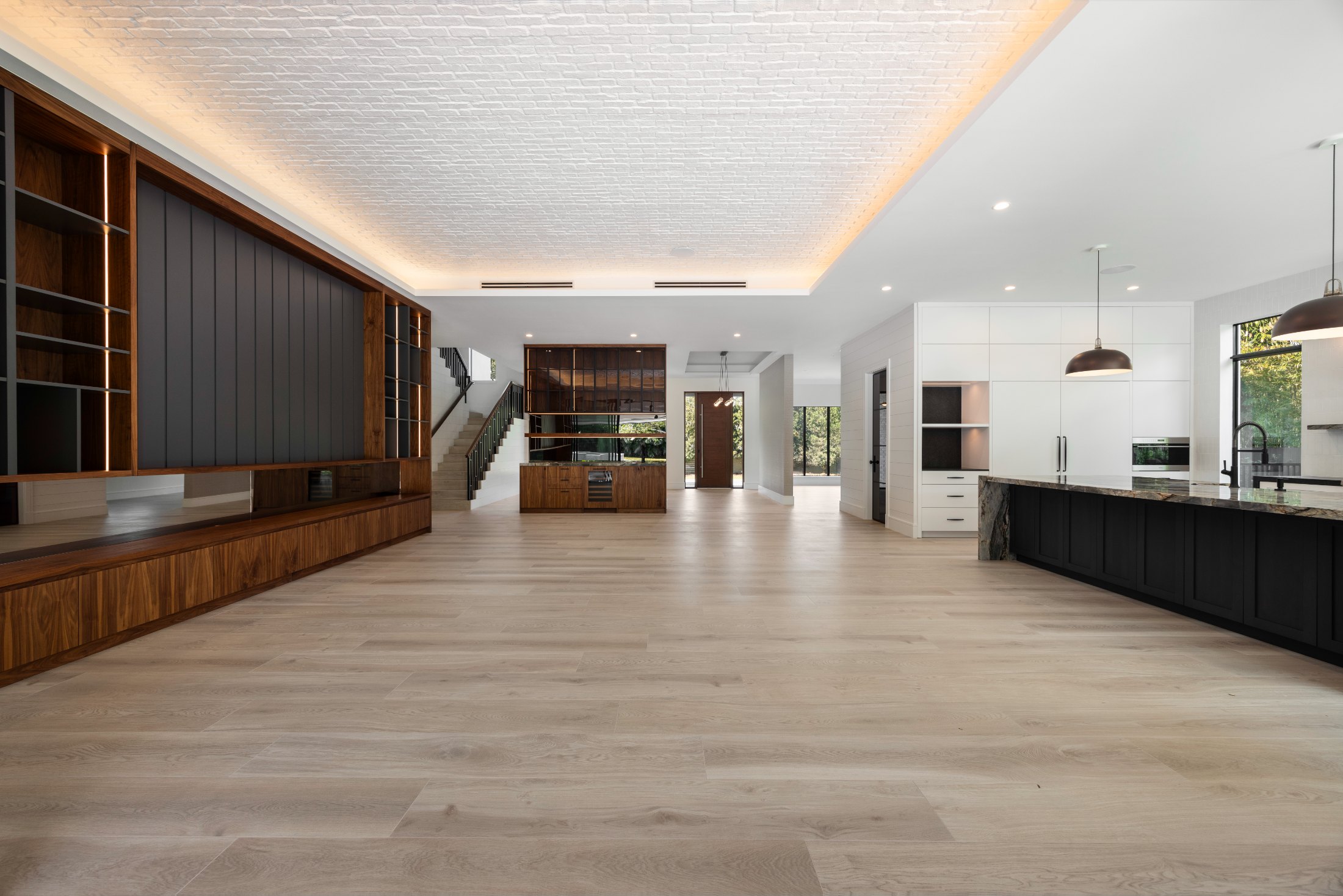 A long walnut built-in wall with integrated lighting beneath an illuminated white brick ceiling